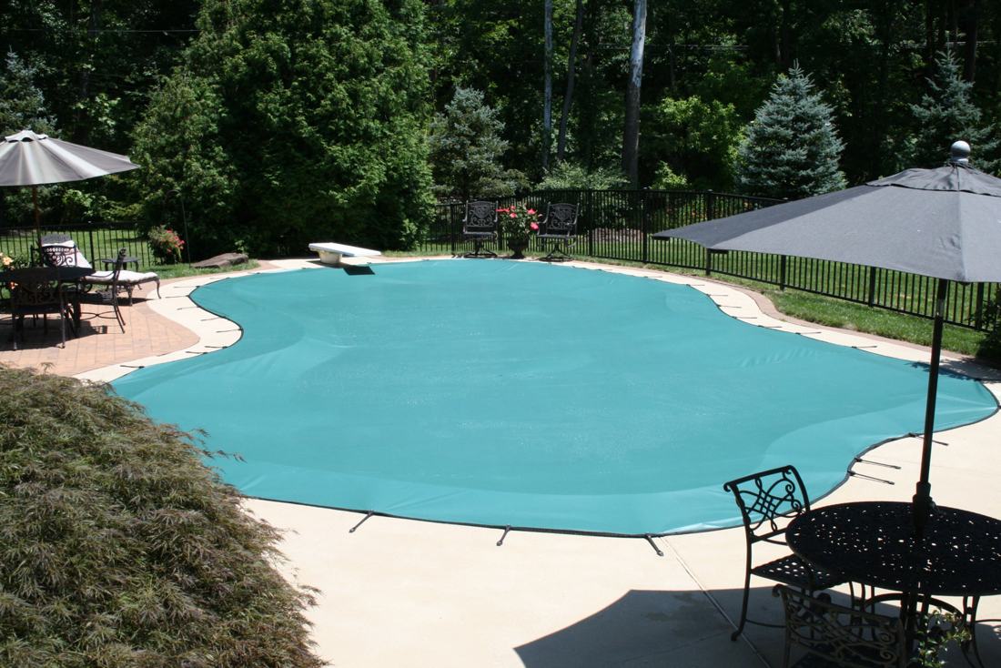 Green safety cover installed on a freeform pool