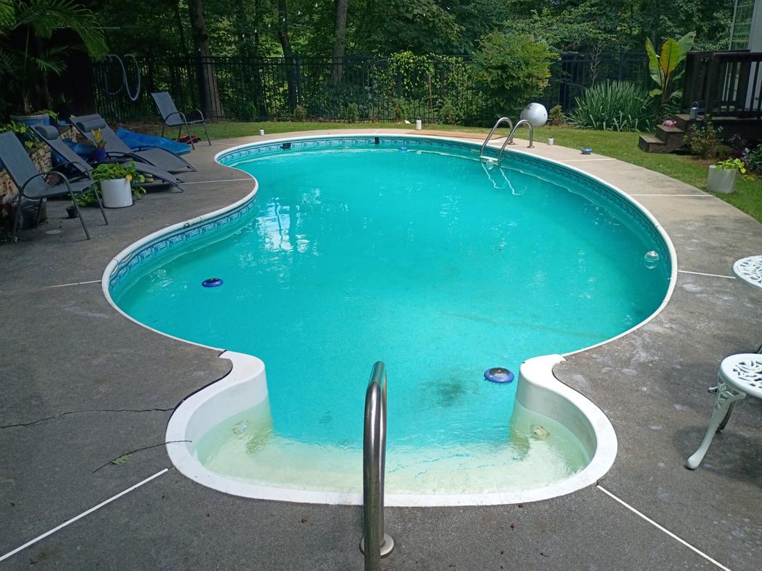 Kidney pool with cloudy water and a faded old liner