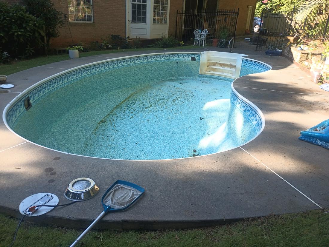 Pool drained, old liner stained and covered in debris