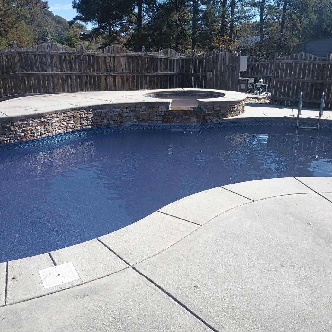 Same kidney pool filled with clear water beside the stone spa
