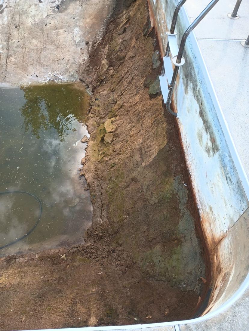 Pool drained, showing the damaged floor and rusted wall