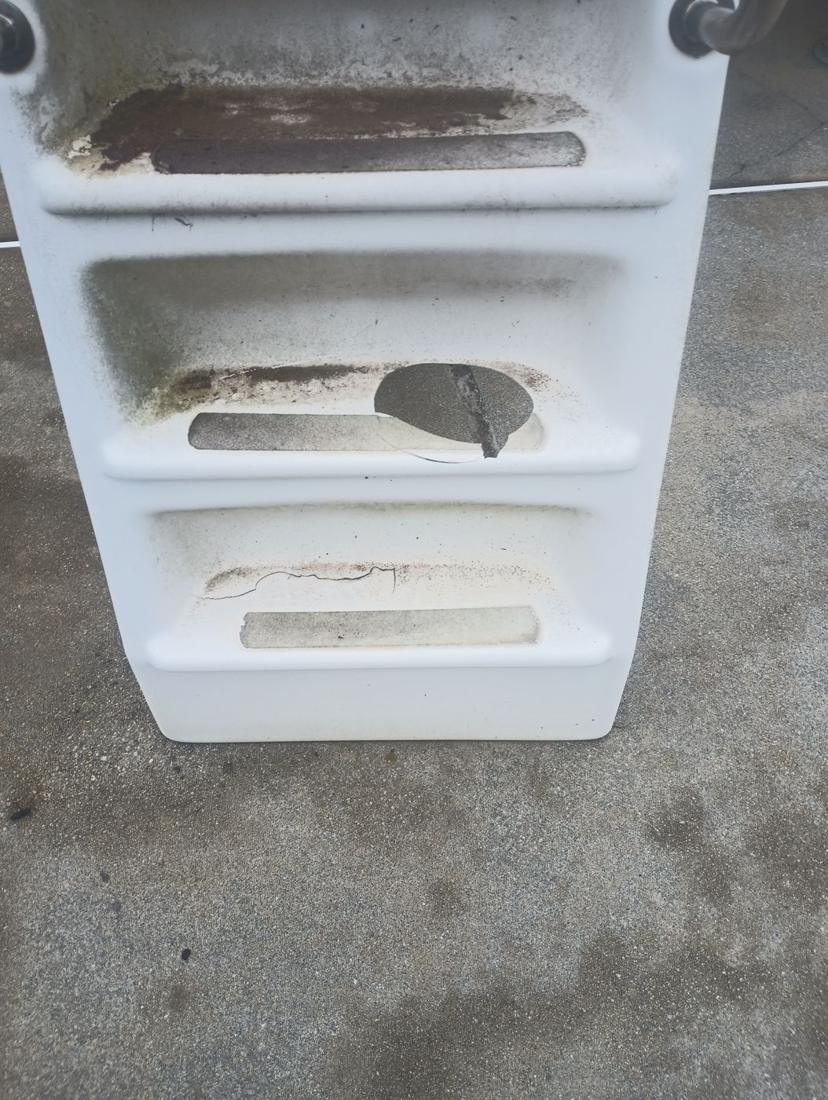Old fiberglass slide steps with cracked, stained treads