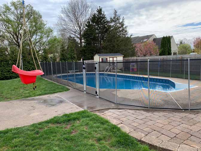 Removable black mesh safety fence around an inground pool